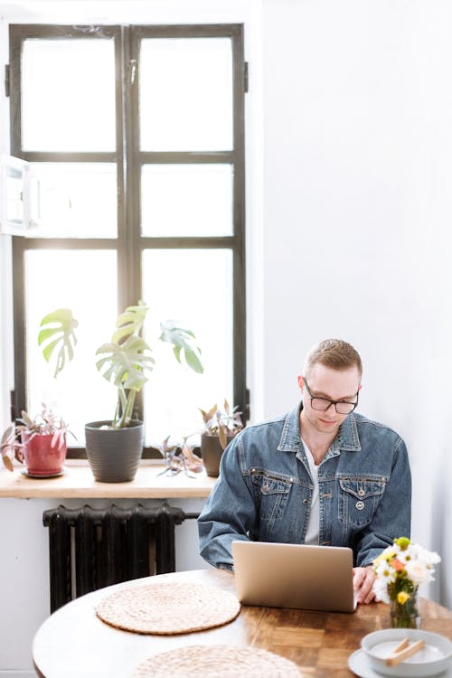Free Man in Blue Denim Jacket Sitting by the Table Stock Photo