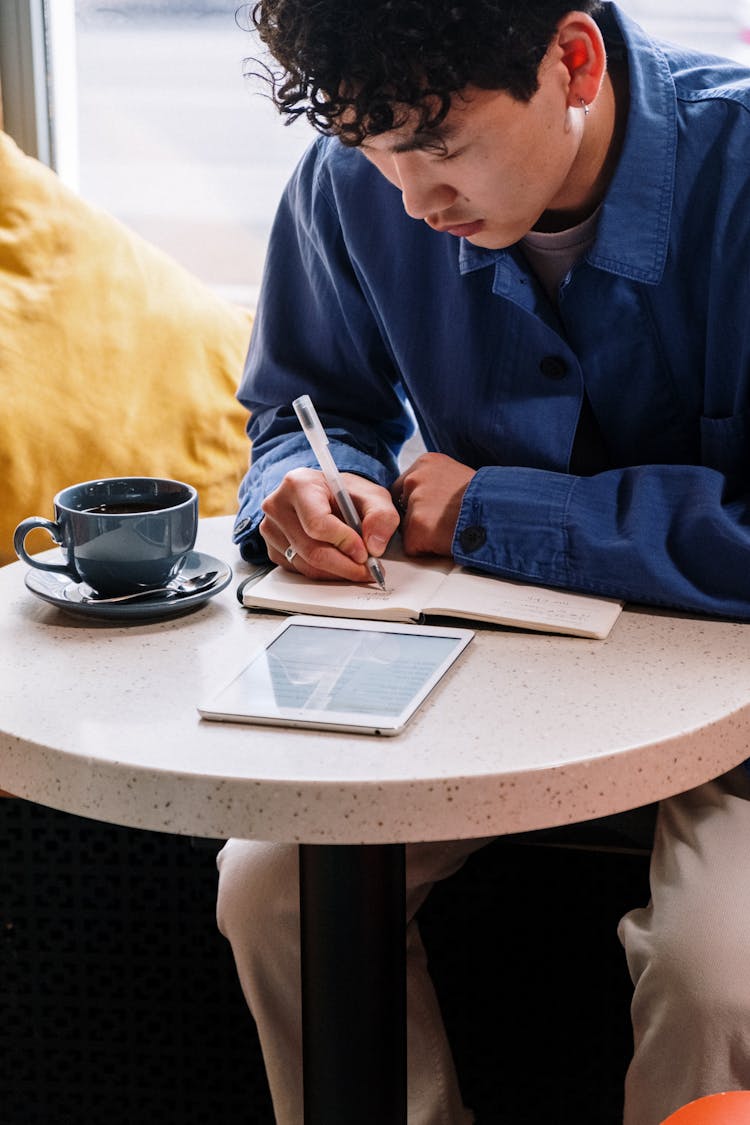 Man In Blue Dress Shirt Writing On White Paper