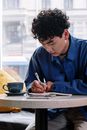 Man in Blue Dress Shirt Writing on White Paper