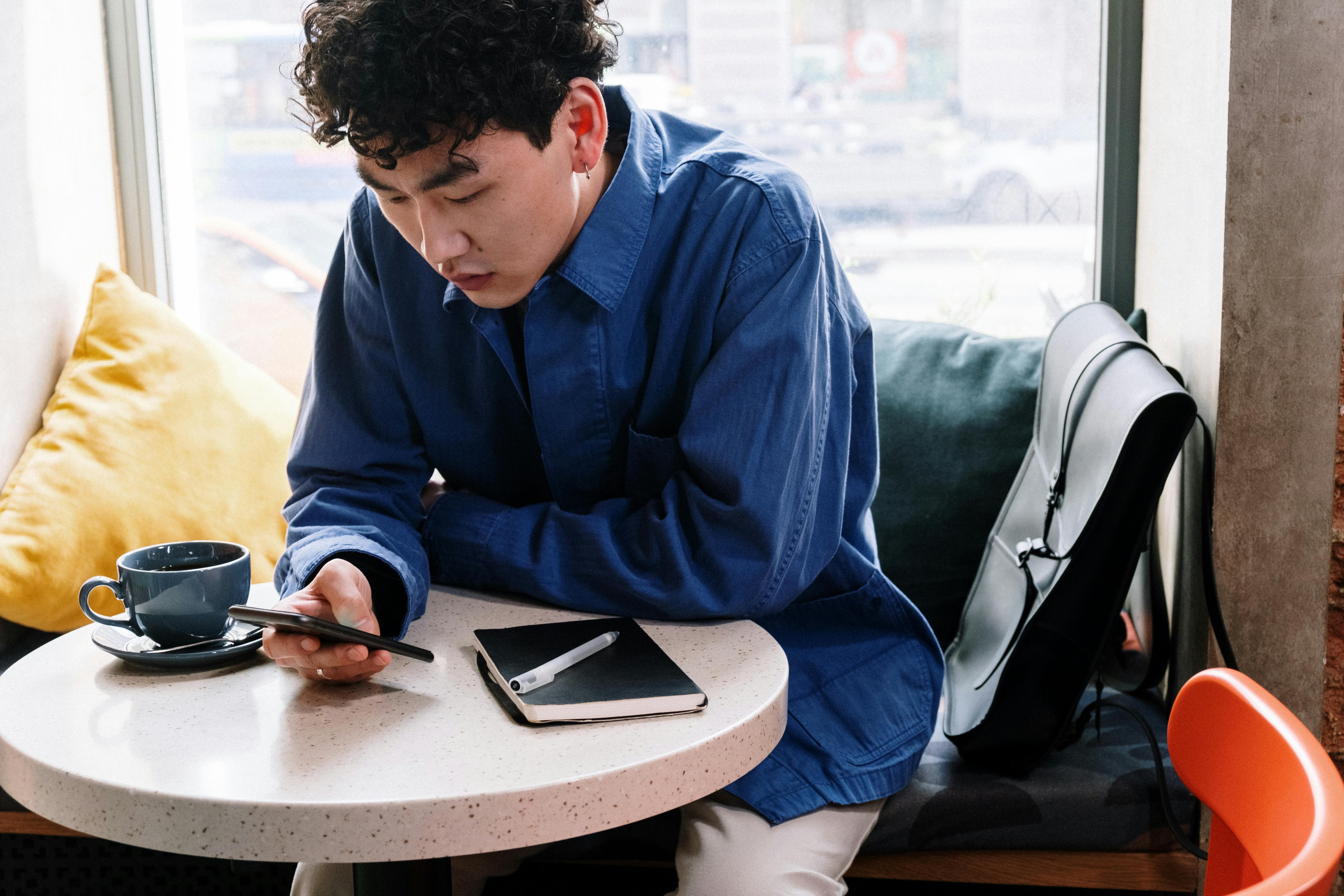 man in blue dress shirt using smartphone