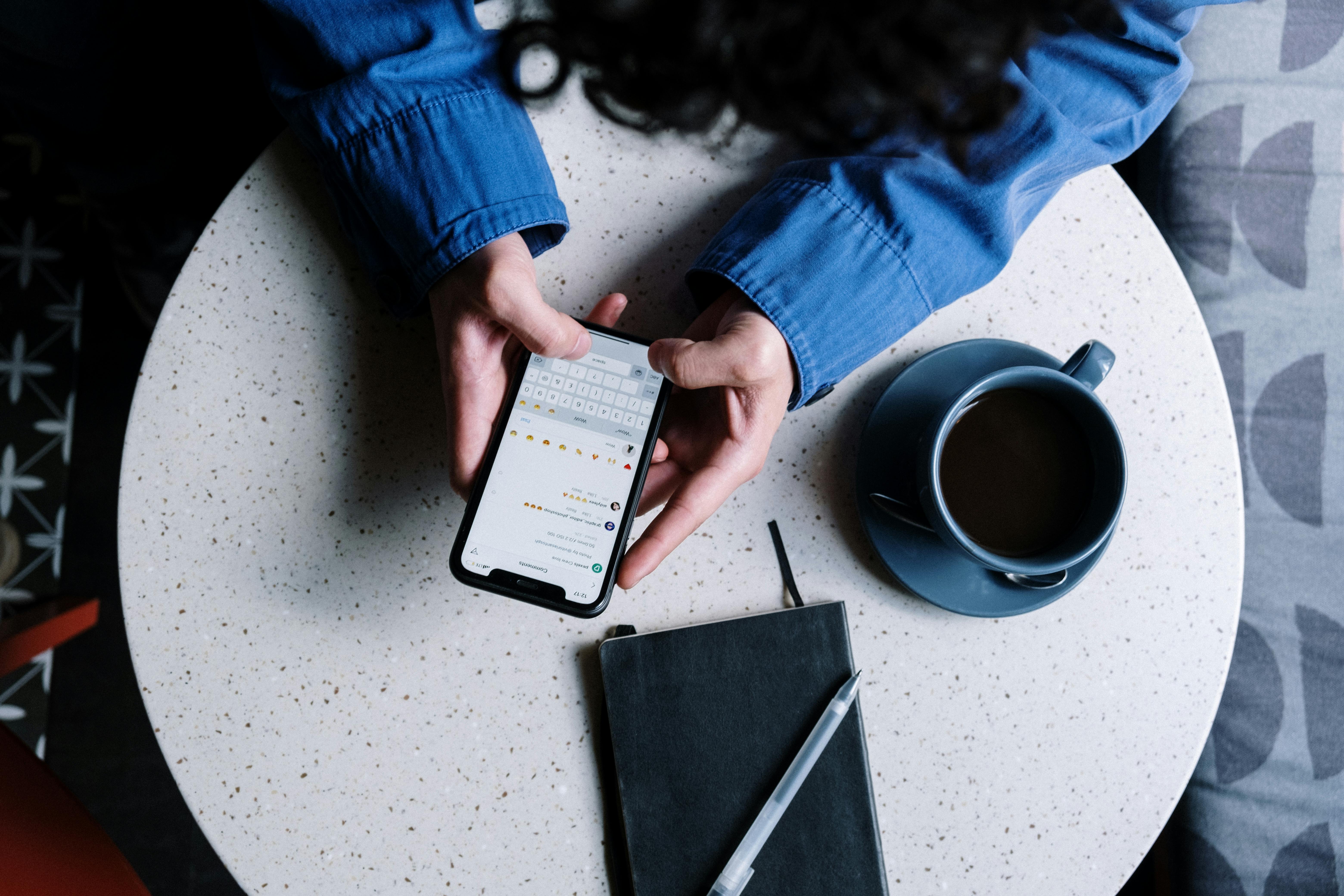 person in blue denim jacket holding black smartphone