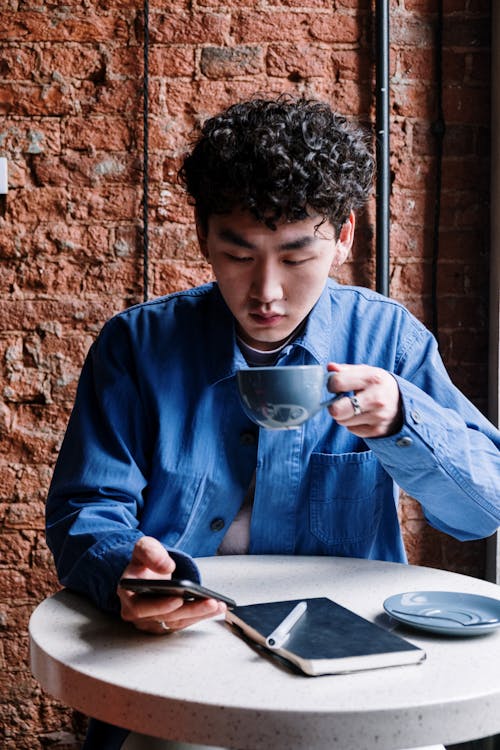 Man in Blue Dress Shirt Holding Silver Iphone 6