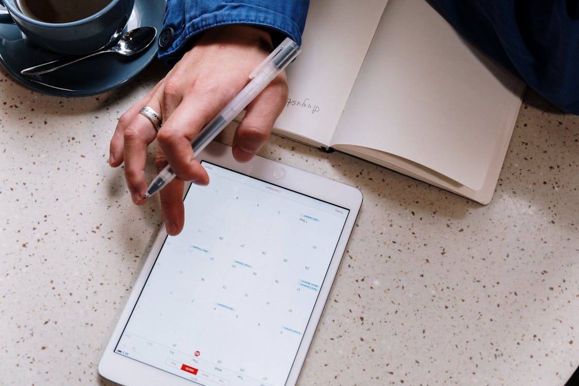 Free Person Holding Pen and Using a Tablet Stock Photo