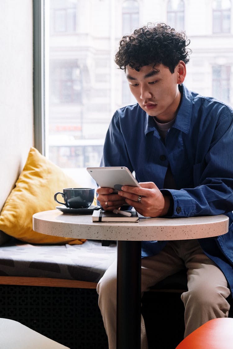 Man In Blue Dress Shirt Sitting On Chair While Reading Book