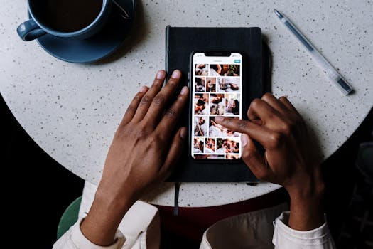 Close-up of hands using smartphone on a cafe table with coffee, highlighting social media browsing.