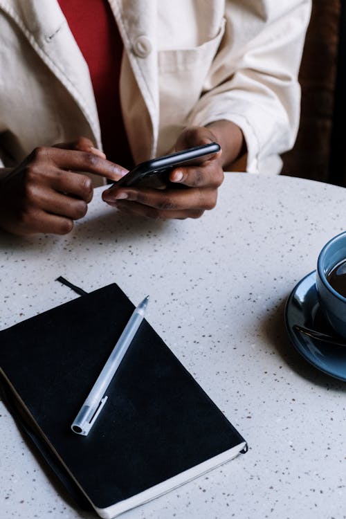 Person Holding Black Smartphone on White Table