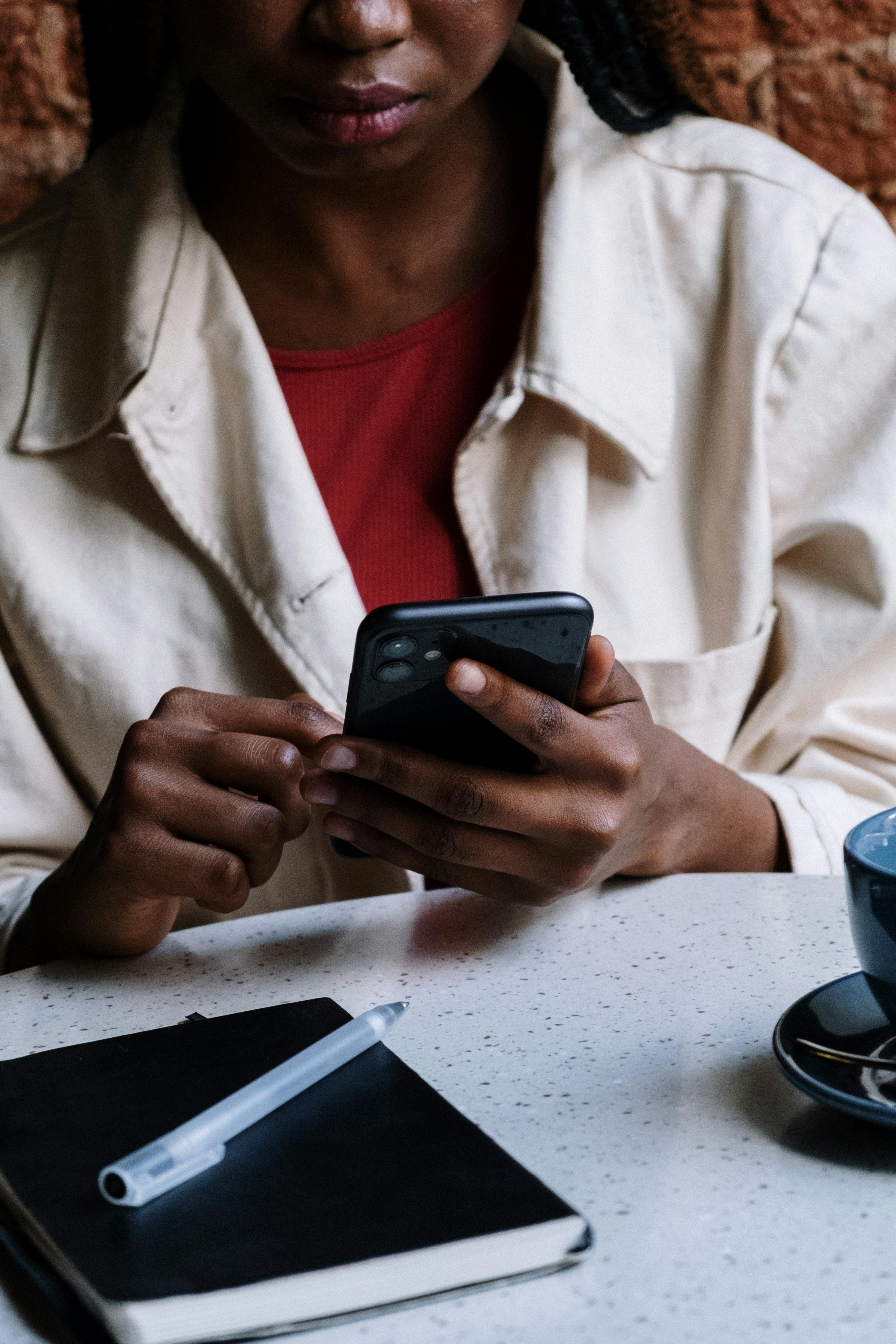 woman in white button up shirt holding black smartphone