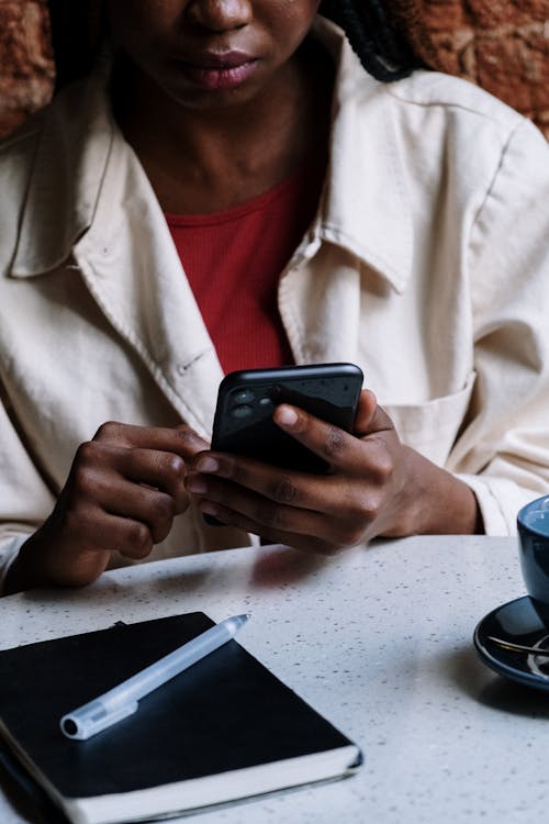 Woman in White Button Up Shirt Holding Black Smartphone