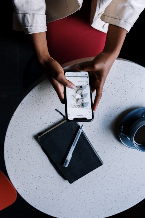 Person Holding Black Ipad on White Round Table