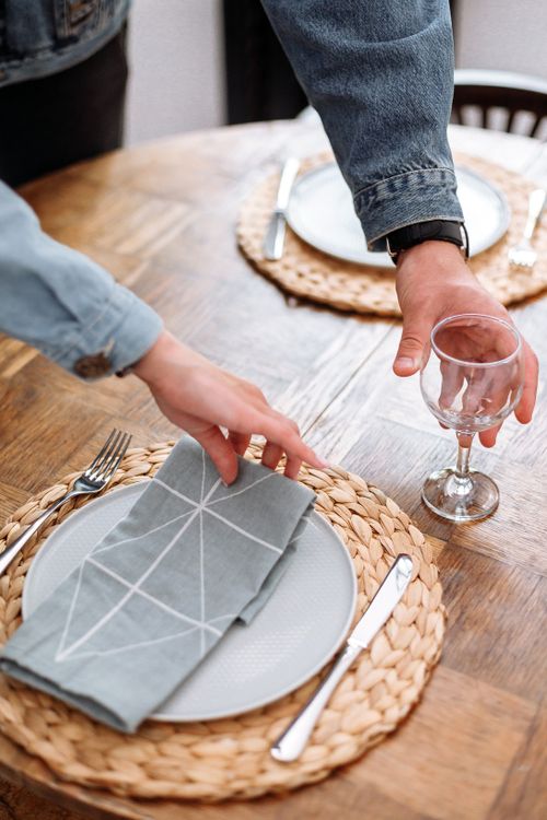 Free Close-up of a stylish table setup with plates, cutlery, and a woven placemat. Stock Photo