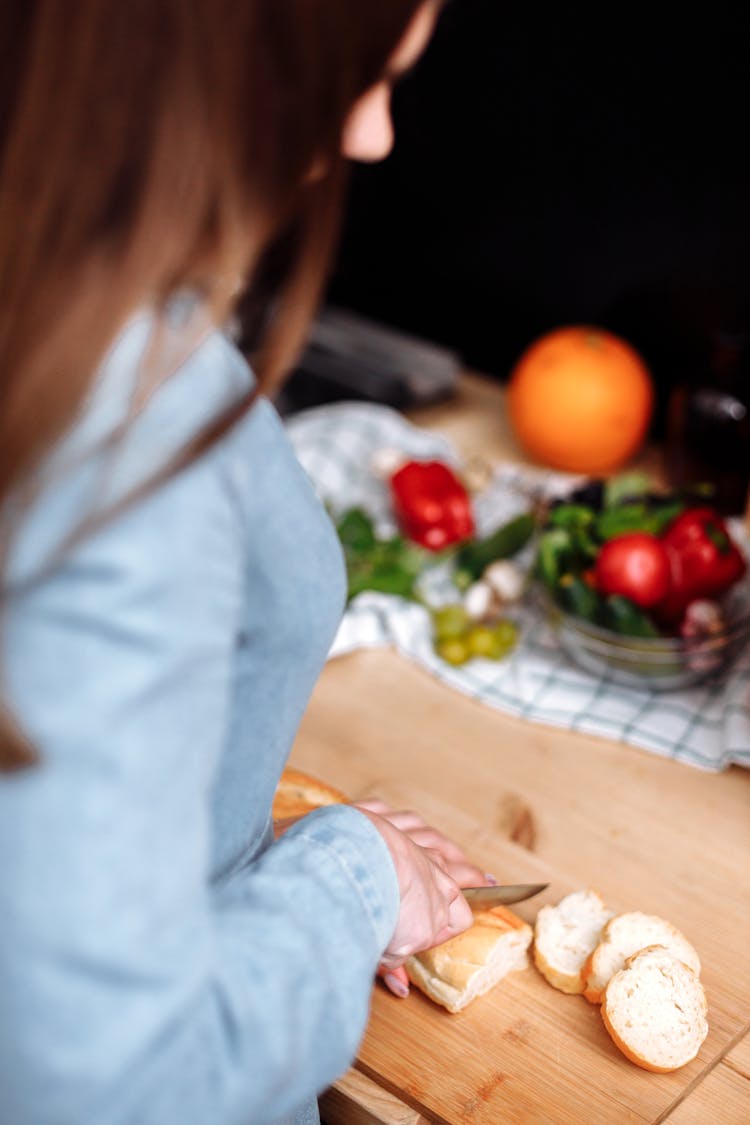 A Woman Slicing A Baguette Bread