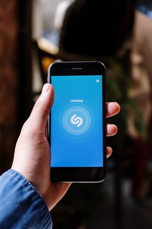 Person Holding an Iphone and Using Shazam