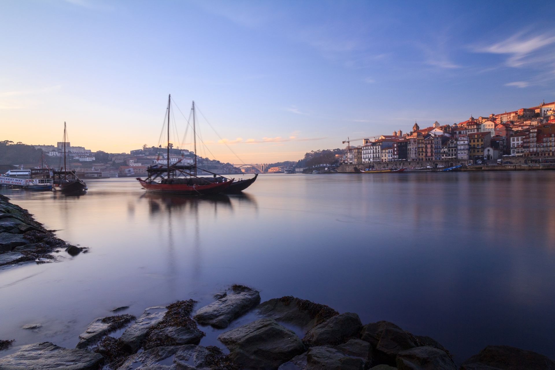Beautiful view of Porto waterfront with sailboats reflecting in calm water during sunset. Perfect travel destination.