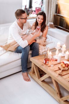 一对夫妇在温暖的氛围中，伴着葡萄酒和蜡烛，享受舒适的室内约会之夜