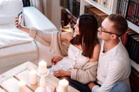 一对情侣在室内幸福地自拍，周围环绕着蜡烛和书籍，营造出舒适的氛围