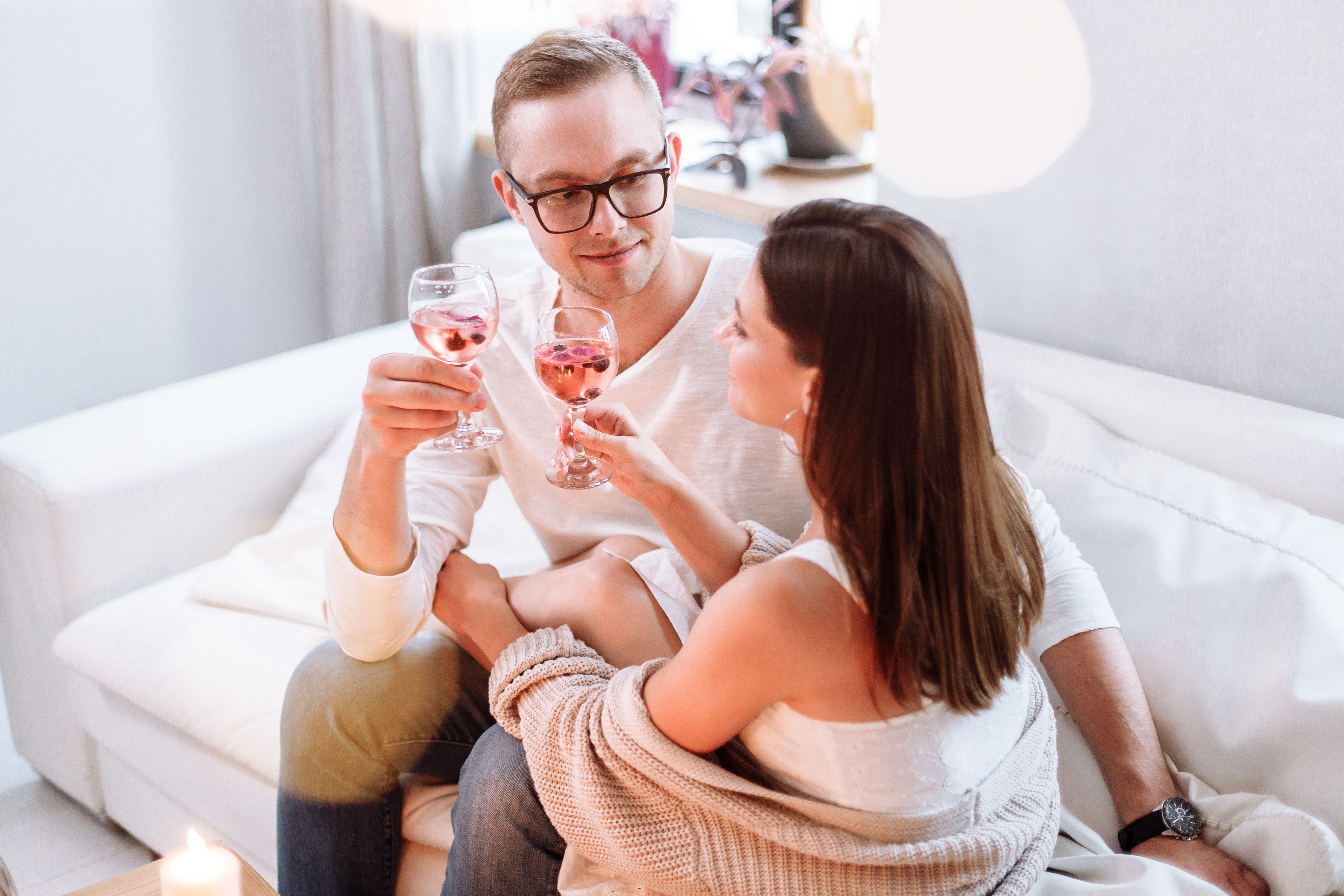 Paar genießt Wein auf dem Sofa vor dem elektrischen Kamin