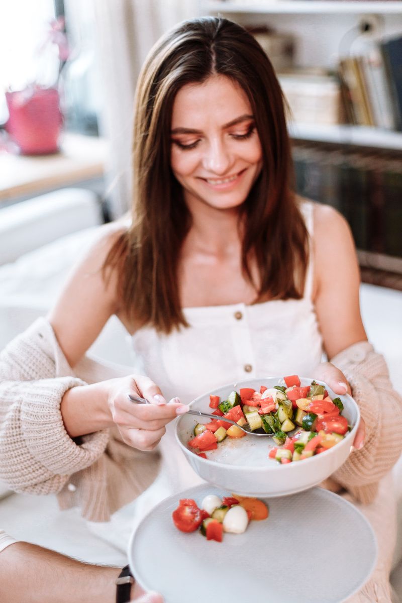 Smiling woman holding a fresh vegetable salad bowl
