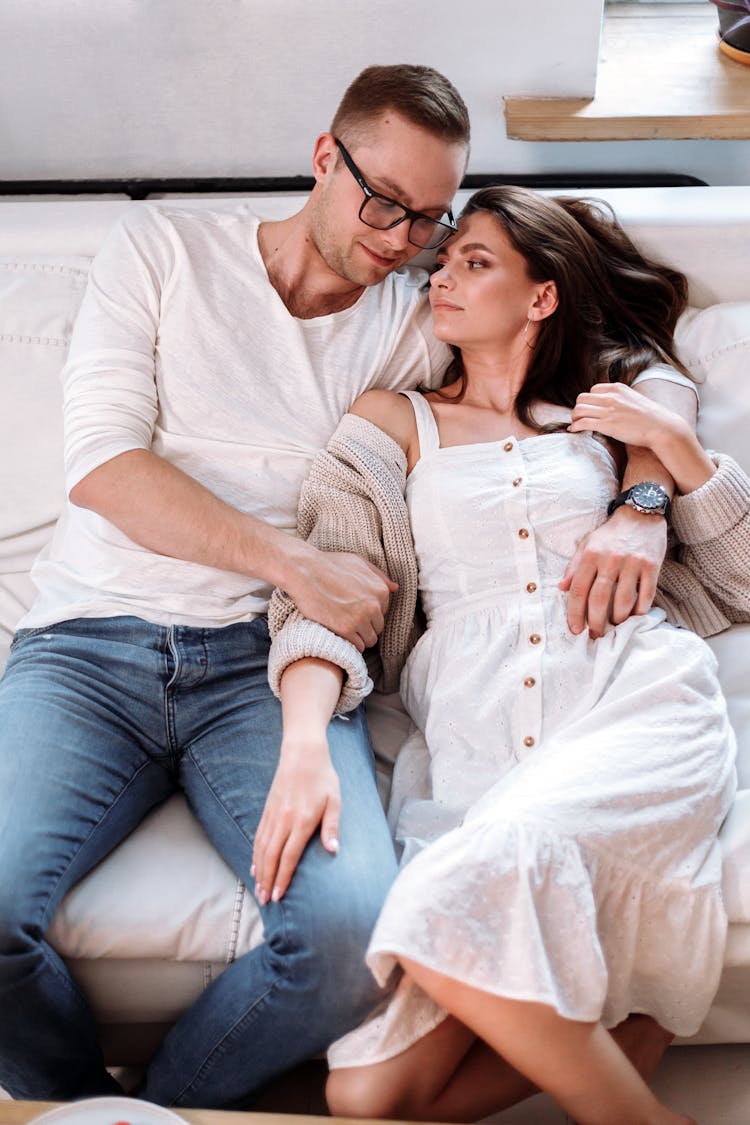 A Couple Sitting On The Couch While Facing Each Other