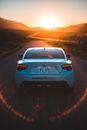 Stylish sport car on highway at sunset