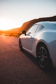 A sleek white sports car travels on an open road during sunset, capturing a sense of freedom and exploration.