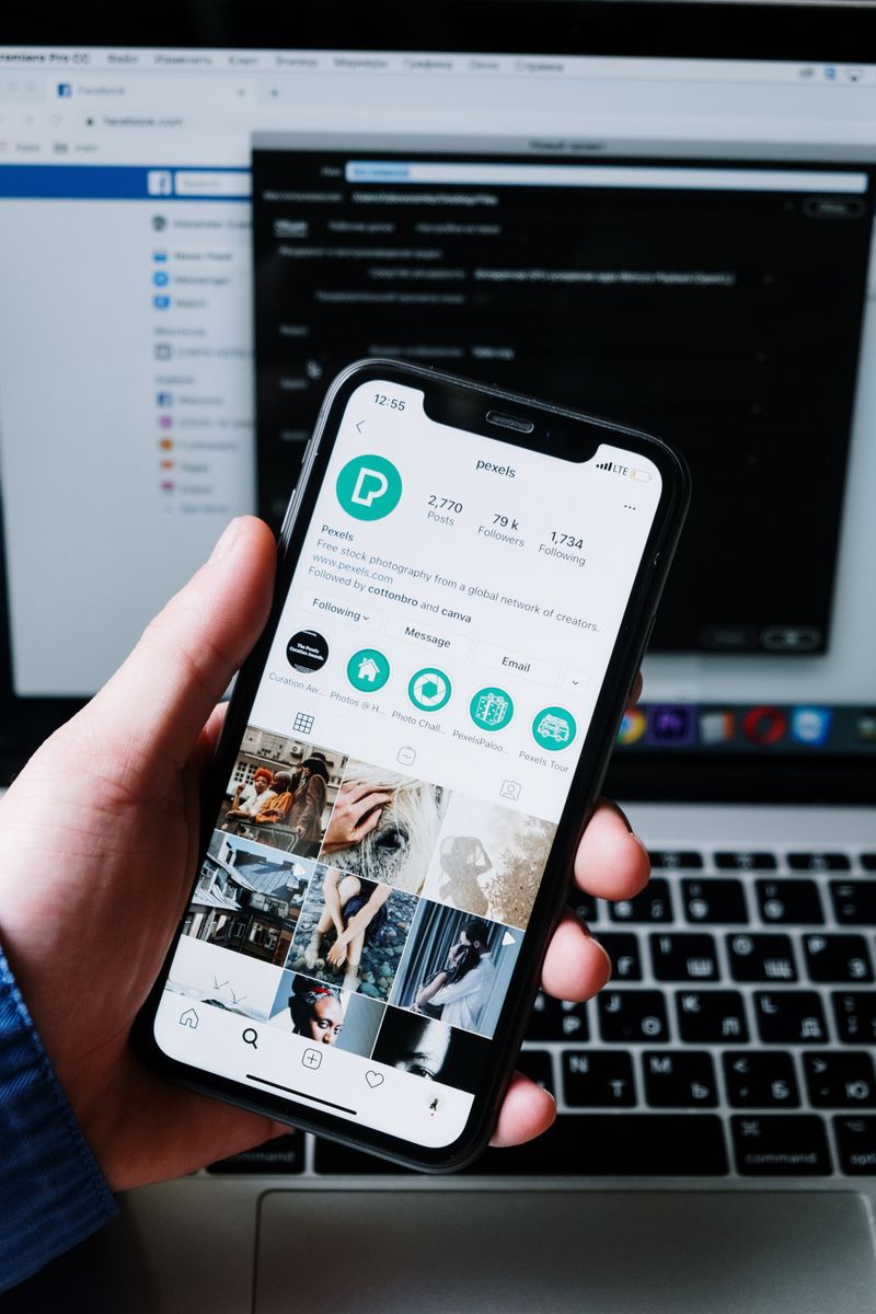 Hand hält ein Smartphone neben einem Laptop – Meta Ads und Google Ads im Vergleich für kleine Budgets.