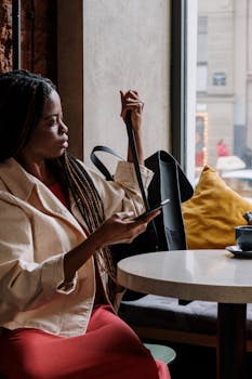 咖啡馆里，一个梳着辫子的时髦女人拿着电话，沉浸在自己的思绪中