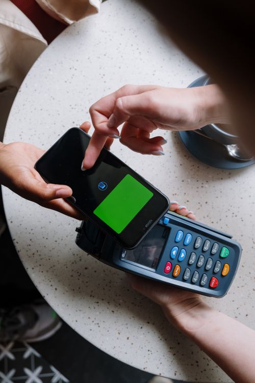 Free A close-up of a smartphone making a contactless payment on a terminal in a cafe setting. Stock Photo