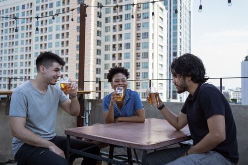Free A group of friends having a fun conversation over beers on a modern rooftop terrace. Stock Photo