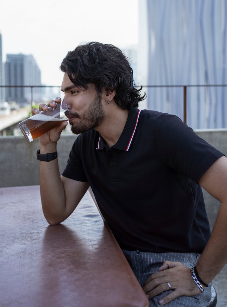 A Bearded Man In Black Polo Shirt Drinking Beer