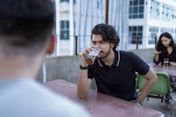 在休闲的户外环境里，一名年轻人正在屋顶露台上喝啤酒