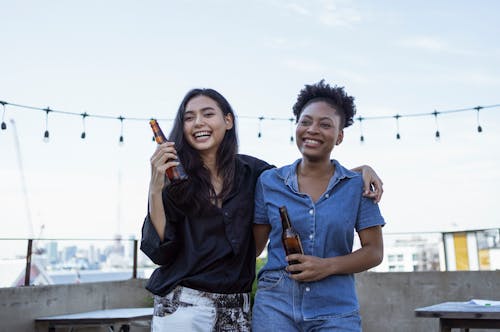 Women Laughing while Holding Beer Bottles