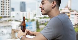 一名成年男子在城市阳台上喝着啤酒放松
