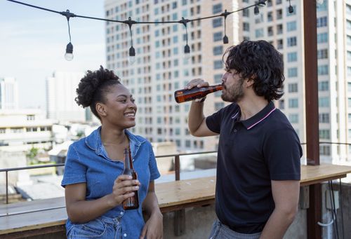 Free Two friends having a good time with beers on a rooftop setting with city buildings in the background. Stock Photo