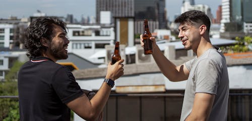 Arkadaşlar, bira şişeleri, birbirine bakmak içeren Ücretsiz stok fotoğraf