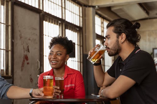 A Man Drinking Beer Near the Woman in Red Shirt Smiling