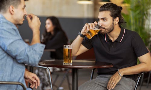 Free A Bearded Man in Black Polo Shirt Drinking Beer Stock Photo