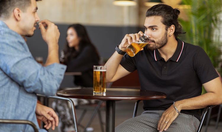 A Bearded Man In Black Polo Shirt Drinking Beer