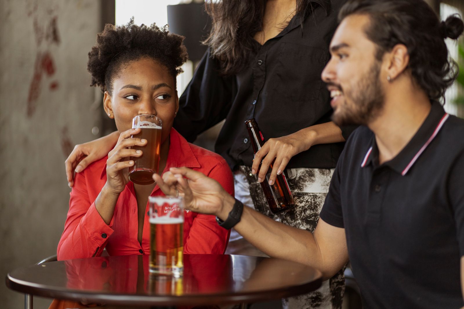 Friends talking over drinks at a wooden pub table