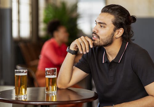 Man Sitting Behind the Table in a Bar with Glasses of Beer on the Table