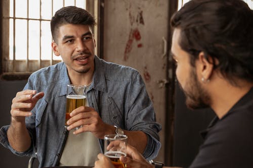 Men Having Conversation while Holding a Glass with Beer