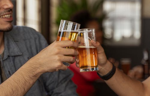 Free A Man Holding a Drinking Glass with Beer while Toasting Stock Photo