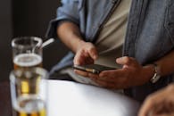 一名男子拿着智能手机坐在咖啡桌旁，周围摆满饮料，这正是通过小工具休闲社交的缩影