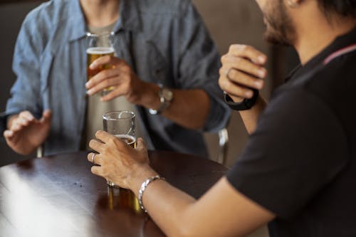 Man in Blue Shirt and Man in Black T-Shirt Holding Glass of Beer