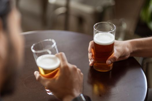 两个人在酒吧餐桌上端着啤酒享用