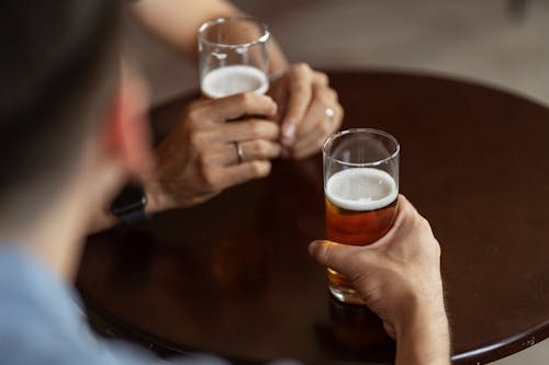 Person Holding Clear Drinking Glass of Beer