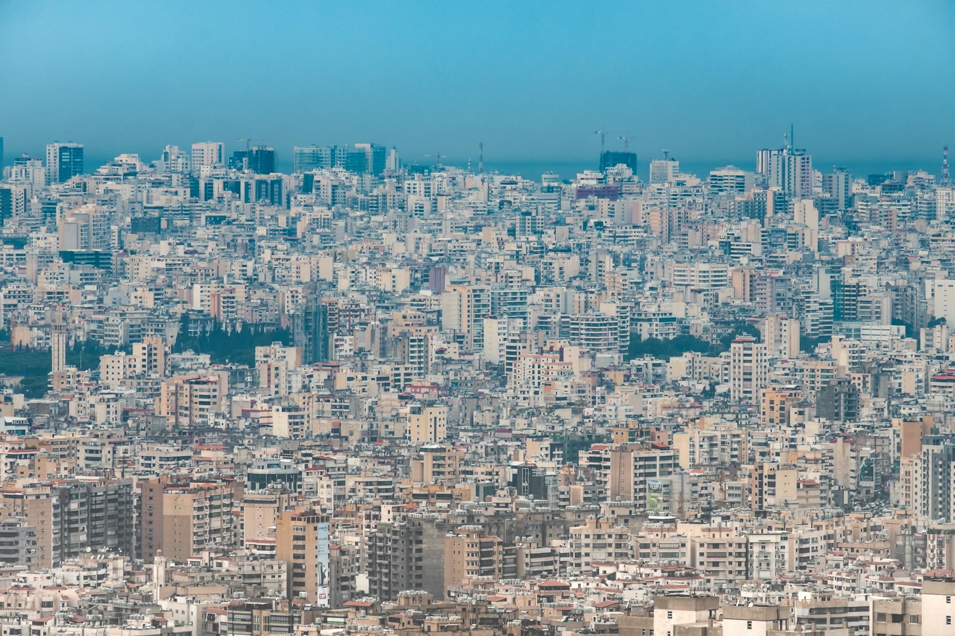 A sprawling aerial view of Beirut's dense urban skyline under a clear blue sky.