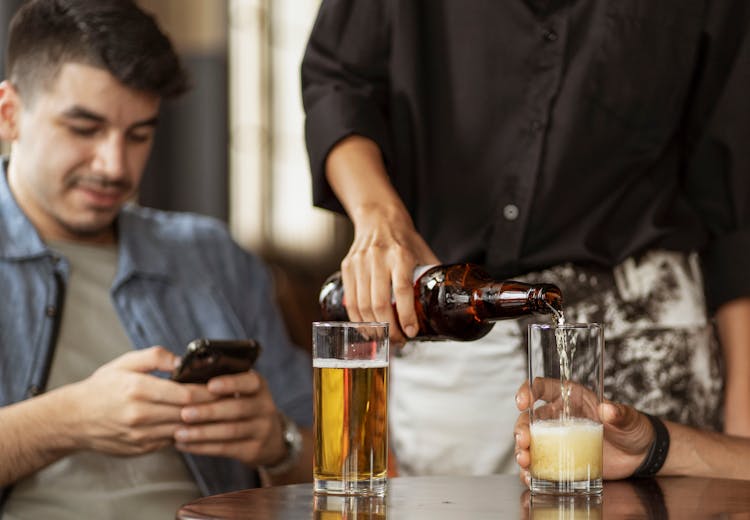 Waiter Pouring Beer Into The Glasses