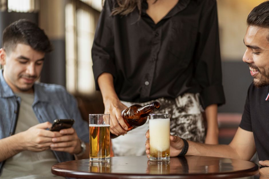 A casual indoor gathering with friends enjoying beers and conversation.