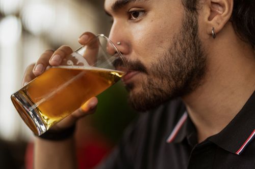 Free Side view of a bearded man sipping beer from a glass at a pub. Stock Photo