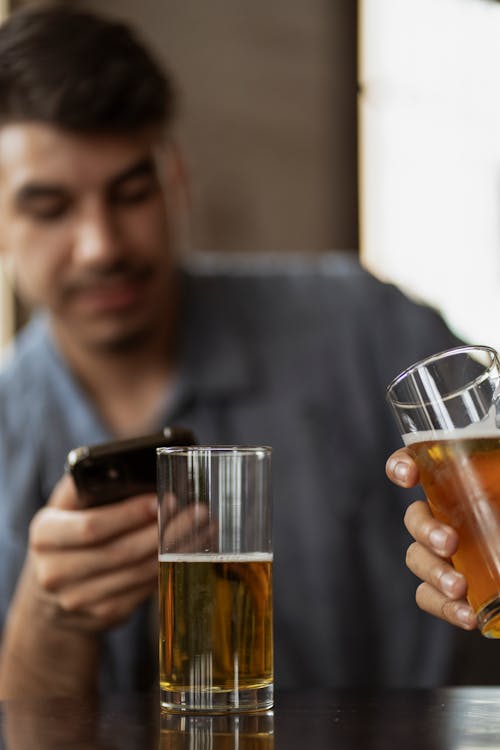 A Man Using His Phone with Beers in Front of Him